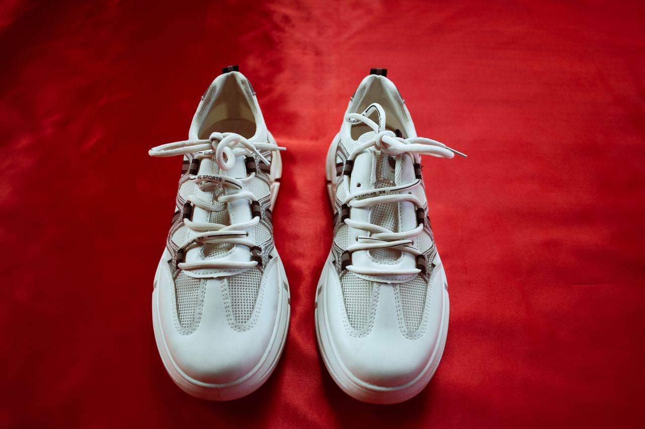 creative-03 Top view of fashionable white sneakers on a bold red background, perfect for footwear fashion and design.